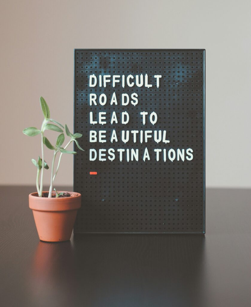 A board that reads "Difficult roads lead to beautiful destinations."